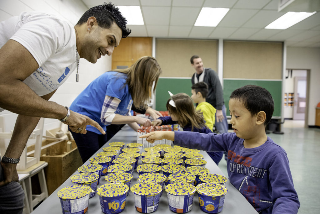 A Backpack Buddies staff member helps a child choose some food items